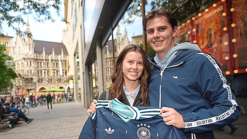 Die Münchner Leonie Blendel und Leon Stokhammer vor Sport Schuster in der Innenstadt: Er hat sich für ein blaues Trikot für 100 Euro entschieden, das zu seinen neuen Schuhen passt. Am Wochenende schauen die beiden mit Freunden das erste Deutschlandspiel. Die Münchner Leonie Blendel und Leon Stokhammer vor Sport Schuster in der Innenstadt: Er hat sich für ein blaues Trikot für 100 Euro entschieden, das zu seinen neuen Schuhen passt. Am Wochenende schauen die beiden mit Freunden das erste Deutschlandspiel.