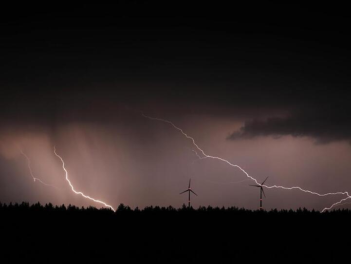 Blitze entladen sich hinter zwei Windrädern. Foto: Karl-Josef Hildenbrand/dpa/Symbolbild
