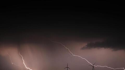 Blitze entladen sich hinter zwei Windrädern. Foto: Karl-Josef Hildenbrand/dpa/Symbolbild