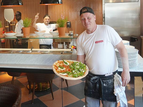 Marius (vorne) und sein Kollege Ali stehen in der offenen Pizzaküche im hinteren Lokalbereich. Marius (vorne) und sein Kollege Ali stehen in der offenen Pizzaküche im hinteren Lokalbereich.