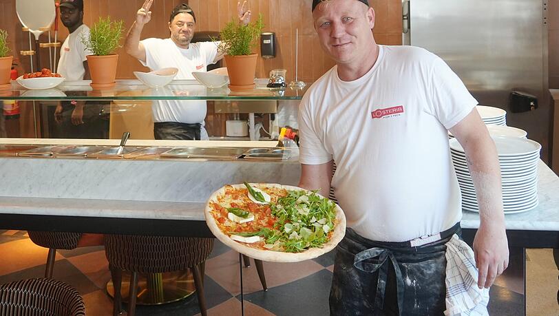 Marius (vorne) und sein Kollege Ali stehen in der offenen Pizzaküche im hinteren Lokalbereich. Marius (vorne) und sein Kollege Ali stehen in der offenen Pizzaküche im hinteren Lokalbereich.
