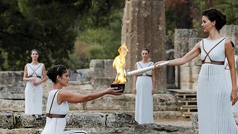 Eine als Hohepriesterin verkleidete Schauspielerin (2.v.r) entzündet 2017 in Olympia eine Fackel an einer Schale mit Feuer.