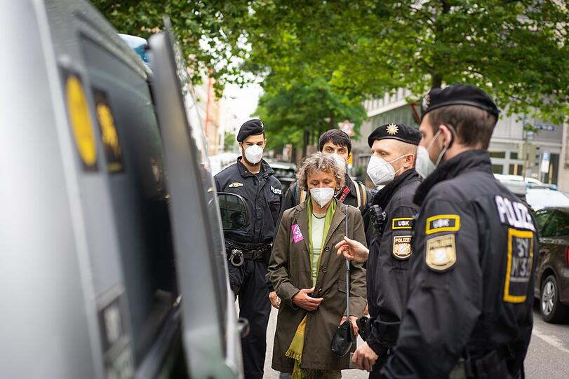 Die Blumenstrauß-Aktivistin, abgeführt von der Polizei. Hinter ihr der Mann, der die Aktion gefilmt hat. Sie kommen beide in die Ettstraße.