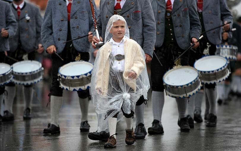 Dieser kleine Bub schützt seine Tracht mit einem Regencape.