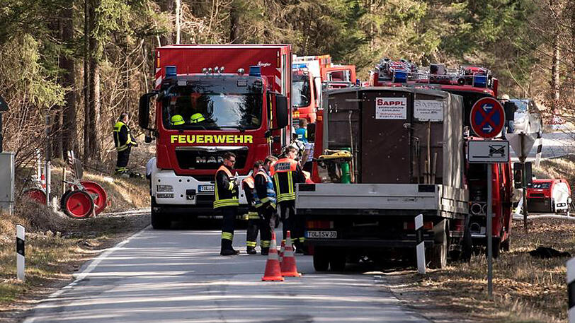 Einsatzkräfte der Feuerwehr stehen in einem Waldstück.