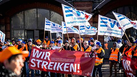 Demonstranten der Eisenbahn- und Verkehrsgewerkschaft (EVG) stehen mit Plakaten vor dem Hauptbahnhof Bremen.