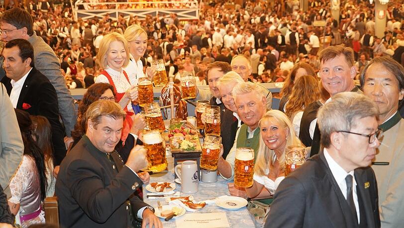 Markus Söder (vorne l.) und Dieter Reiter haben nach dem Anstich die Ratsboxe im Schottenhamel-Zelt erklommen und stoßen mit ihren Frauen und Ehrengästen an.