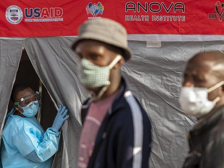 Menschen stehen in Johannesburg vor einem Zelt an, um sich auf eine Infektion mit dem Coronavirus testen zu lassen.