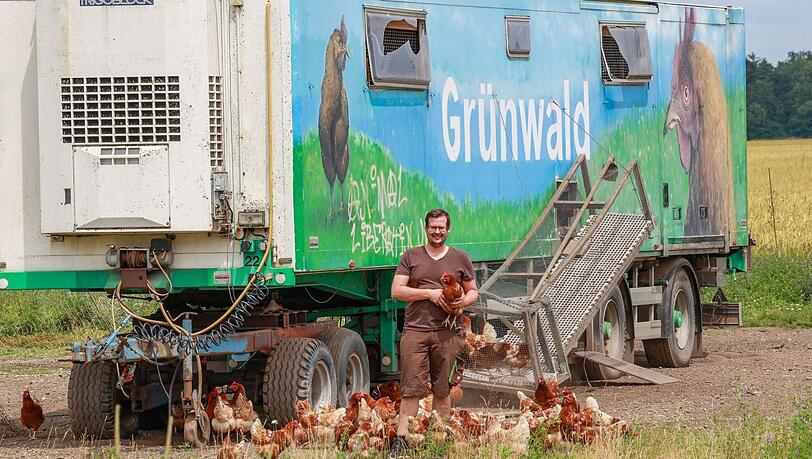 Bauer Andreas Grünwald mit seinen braunen Bovans-Hühnern: Sein mobiler Hühnerstall ist ein umgebauter Kühlwagen und steht auf einer Wiese vor seinem Hof im Ortsteil Ludwigsfeld.