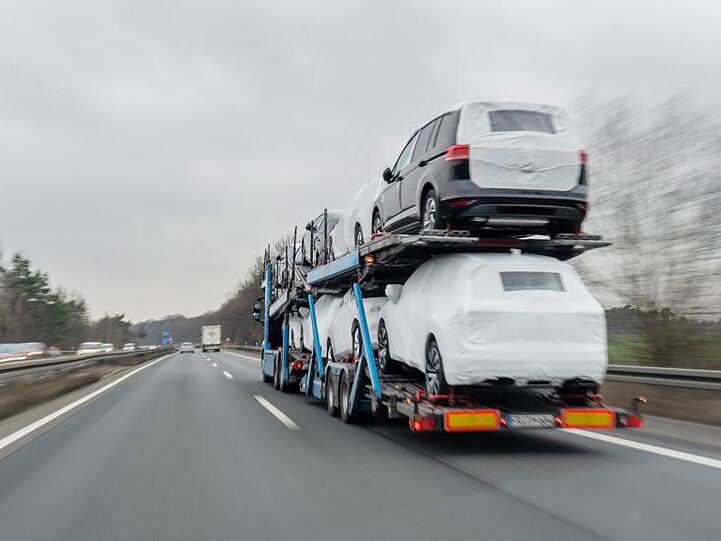 Ein Autotransporter mit Neuwagen fährt über eine Bundesstraße.