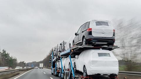 Ein Autotransporter mit Neuwagen fährt über eine Bundesstraße.