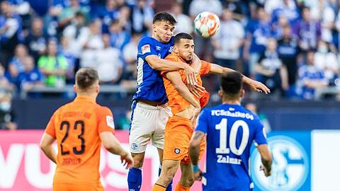 Schalkes Mehmet Aydin (2.v.l.) und Aues Soufiane Messequem (2.v.r.) gehen zum Kopfballduell hoch.
