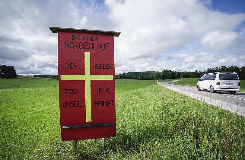 Ein Protestschild mit der Aufschrift "Brenner Nordzulauf - Der gelbe Tod für unsere Heimat" einer Bürgerinitiative steht auf einer Wiese der geplanten Bahntrasse.