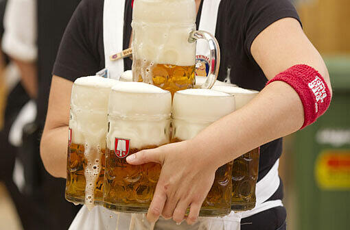Eine Bedienung traegt in Muenchen auf dem Oktoberfest im Schottenhamel-Festzelt Bierkruege.