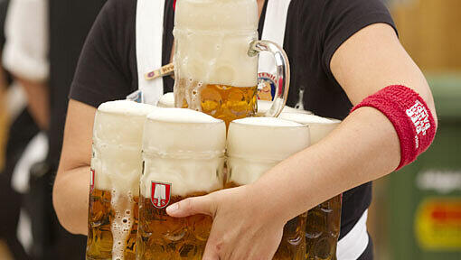 Eine Bedienung traegt in Muenchen auf dem Oktoberfest im Schottenhamel-Festzelt Bierkruege. Eine Bedienung traegt in Muenchen auf dem Oktoberfest im Schottenhamel-Festzelt Bierkruege.
