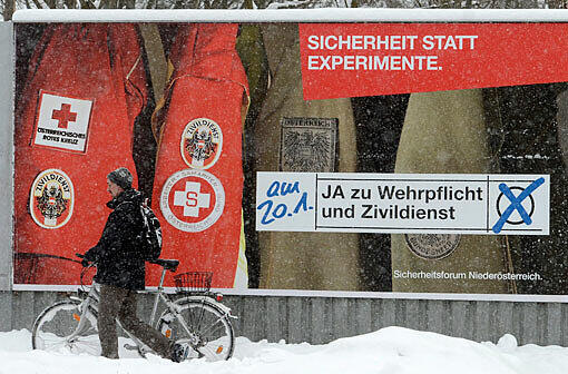 Ein Mann schiebt in St. Pölten (Bundesland Niederösterreich) sein Rad vorbei an einem Wahlplakat. Die Befürworter der Wehrpflicht liegen vor der Volksbefragung am Sonntag in den Umfragen vorne.