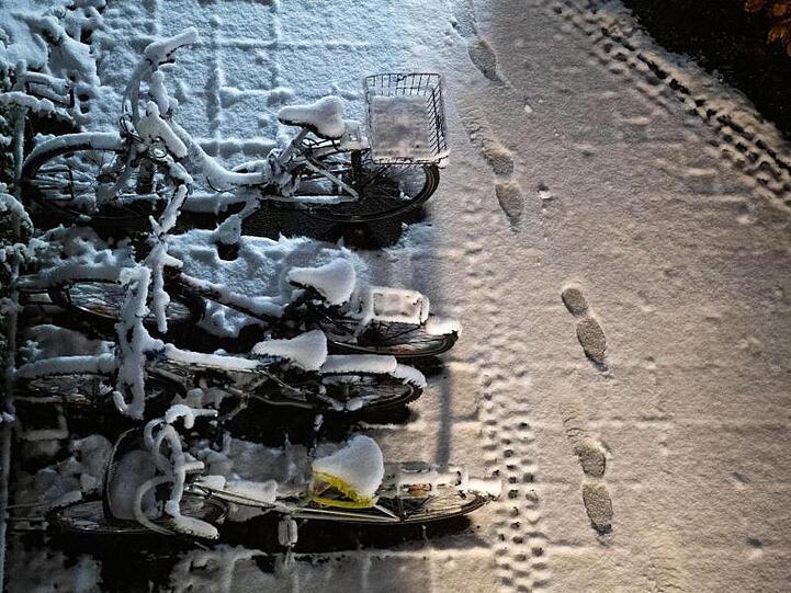 Fußspuren sind im frischen Schnee neben einem Fahrradständer zu sehen. Foto: Lino Mirgeler