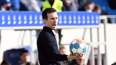 Der Karlsruher Trainer Christian Eichner ruft und hält einen Ball in der Hand.