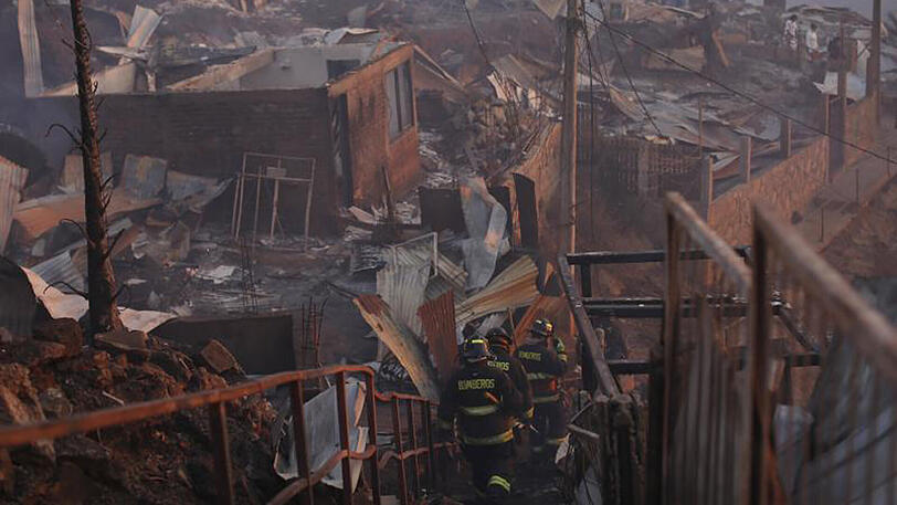 Feuerwehrmänner in einem von den Flammen zerstörten Vietel der Stadt Valparaíso.