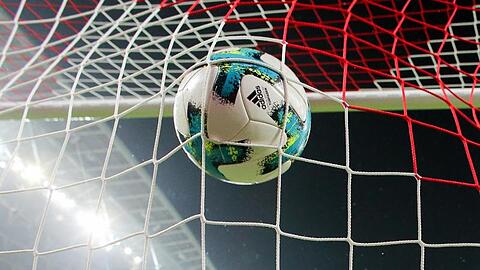 Ein Fußball fliegt ins Netz.