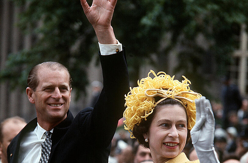 Mai 1965: Elizabeth II. und ihr Gatte Prinz Philip winken während ihrer Fahrt durch Berlin aus einem offenen Wagen der Bevölkerung zu.
