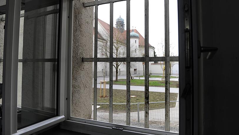 Hinter-Gitter-Blick vom Gefängnisflur nach draußen in den Innenhof Hinter-Gitter-Blick vom Gefängnisflur nach draußen in den Innenhof