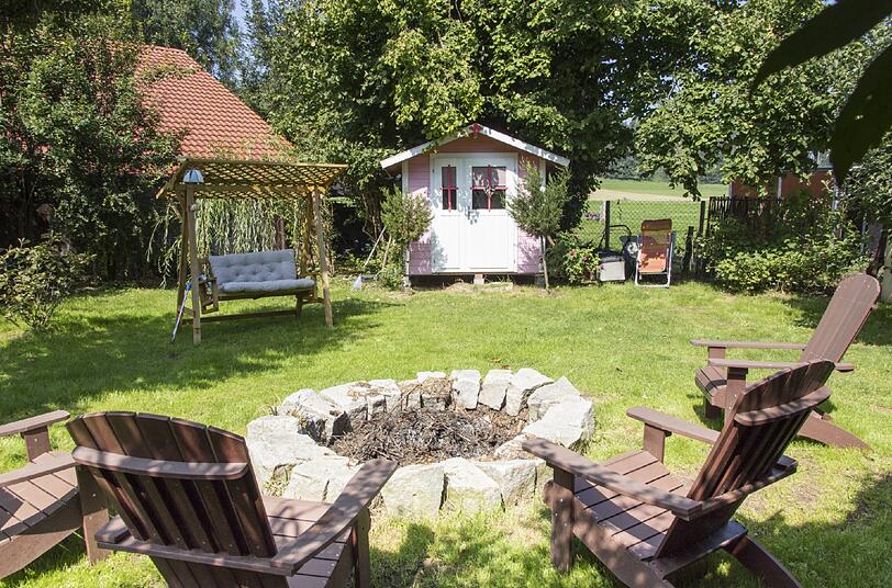 Gemütliche Oase: Der große Garten mit einer Lagerfeuerstelle lädt zum Verweilen ein. Als Sichtschutz dient ein Zaun aus Haselnuss-Ästen.