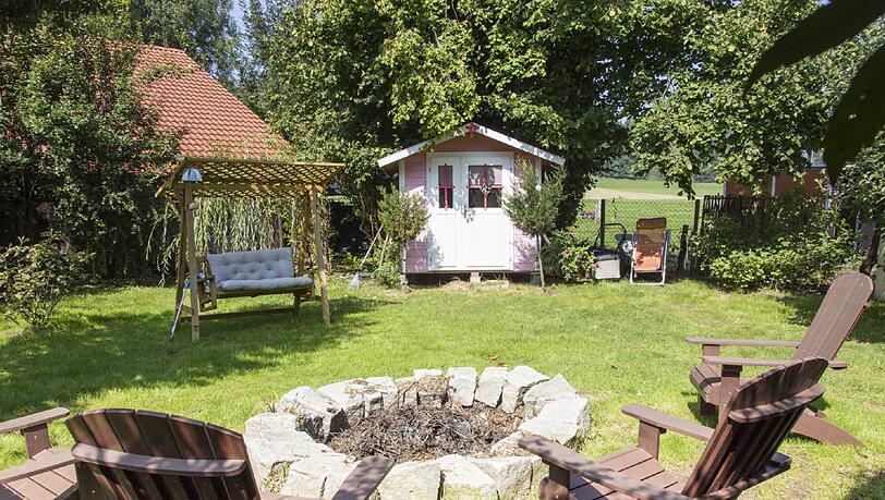 Gemütliche Oase: Der große Garten mit einer Lagerfeuerstelle lädt zum Verweilen ein. Als Sichtschutz dient ein Zaun aus Haselnuss-Ästen.