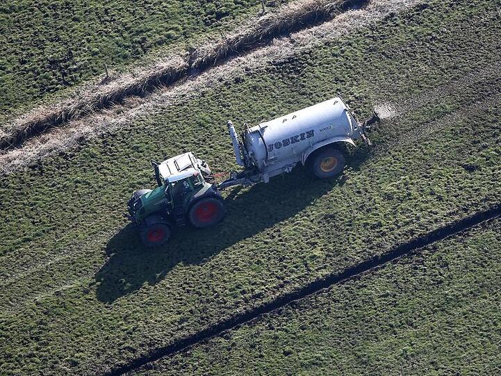 Ein Traktor verteilt Gülle auf einem Feld. Foto: Axel Heimken/dpa/Archivbild