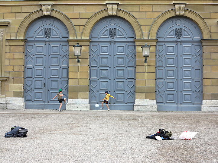 Samstagnachmittag vor der Residenz im Hofgarten: eine Gruppe Buben spielt Fußball in exklusivem Ambiente.