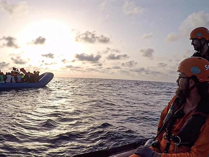 Seenotretter vom Rettungsschiff "Alan Kurdi" blicken zu einem Schlauchboot voller Flüchtlinge (Archiv).