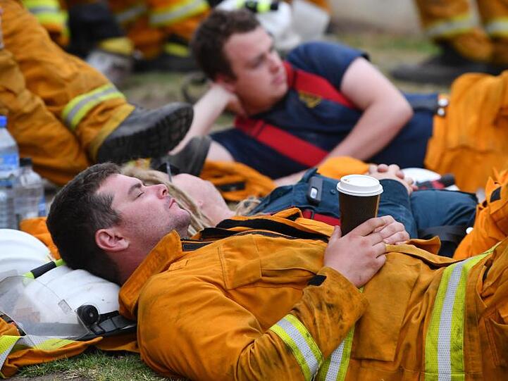 Erschöpfte Feuerwehrleute ruhen sich während eines Einsatzes gegen Buschbrände bei Adelaide aus.