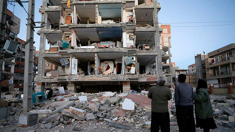 In Sarpol-E-Zahab, Iran, stehen Überlebende vor einem zerstörten Haus.