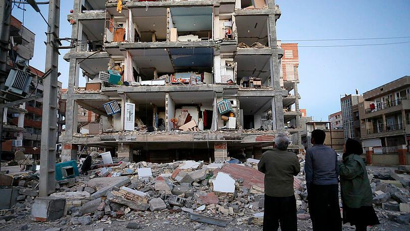 In Sarpol-E-Zahab, Iran, stehen Überlebende vor einem zerstörten Haus. In Sarpol-E-Zahab, Iran, stehen Überlebende vor einem zerstörten Haus.