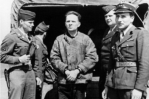 Das Foto entstand am Nürnberger Flughafen. Schwer bewacht wird Rudolf Höß nach Polen gebracht.