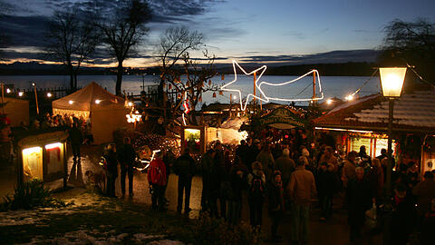 Ausflügler besuchen am zweiten Advent-Sonntag bei Abenddämmerung den Christkindlmarkt auf der Fraueninsel im Chiemsee (Archiv).