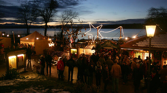 Ausflügler besuchen am zweiten Advent-Sonntag bei Abenddämmerung den Christkindlmarkt auf der Fraueninsel im Chiemsee (Archiv).