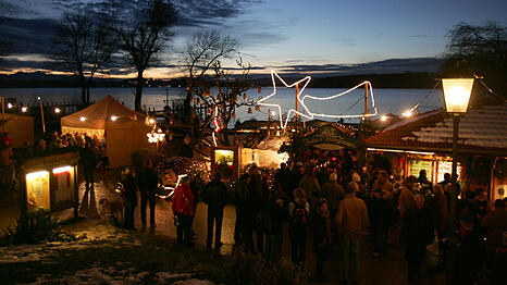 Ausflügler besuchen am zweiten Advent-Sonntag bei Abenddämmerung den Christkindlmarkt auf der Fraueninsel im Chiemsee (Archiv).