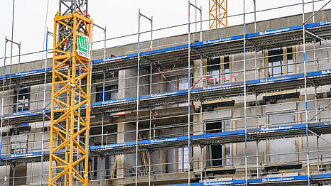 An einem im Bau befindlichen Geb&auml;ude des sozialen Wohnungsbaus sind Fassadenelemente montiert, das Haus ist von einem Bauger&uuml;st umgeben. (Symbolbild)