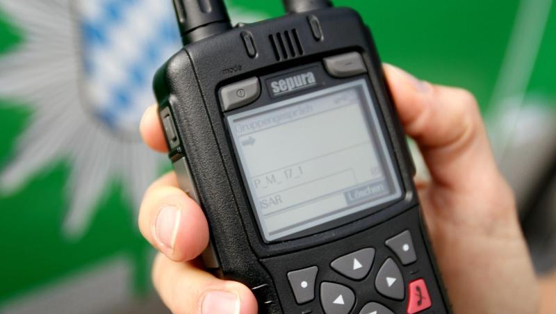 Eine Polizeibeamtin hält ein Digitalfunkgerät vor ein Polizeiauto. Foto: Lukas Barth/Archivbild Eine Polizeibeamtin hält ein Digitalfunkgerät vor ein Polizeiauto. Foto: Lukas Barth/Archivbild