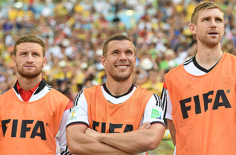 Prominente Bankdrücker: Shkodran Mustafi und Per Mertesacker (rechts) nehmen am Rande des Viertelfinalspiels gegen Frankreich bei der WM 2014 ihren Kollegen Lukas Podolski in die Mitte.