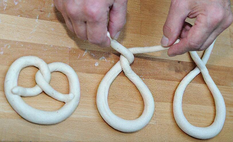 Fünf Bäcker schlingen bei Rischart bis zum Morgengrauen Brezn. Die langen Teigwürste, werfen sie so schnell, dass in nicht mal einer Sekunde, die Breze geformt ist.
Zuerst wird der Teig leicht auseinandergezogen, damit die Enden dünner sind als der Rest. Dann werden diese Enden der Teigschlange überkreuzt, danach noch einmal um die eigene Achse gedreht. 
Die beiden Enden werden dann nach unten geklappt und auf den Bögen festgedrückt. Maschinen kommen bei Rischart nicht zum Einsatz.