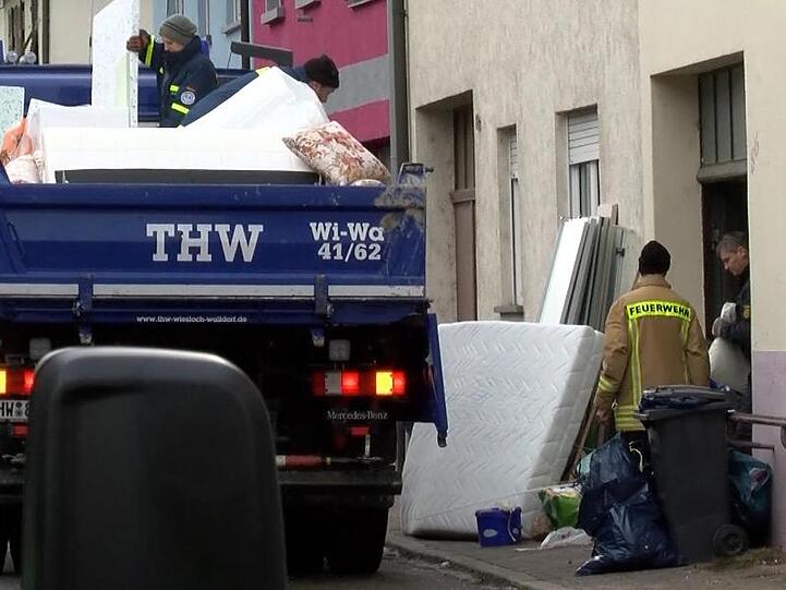 Polizisten und Helfer des Technischen Hilfswerks (THW), räumen Möbelstücke aus einer Wohnung in Plankstadt. Beamte des SEK haben Mittwochabend zwei Wohnungen in Mannheim und je eine in Plankstadt und Reilingen durchsucht.