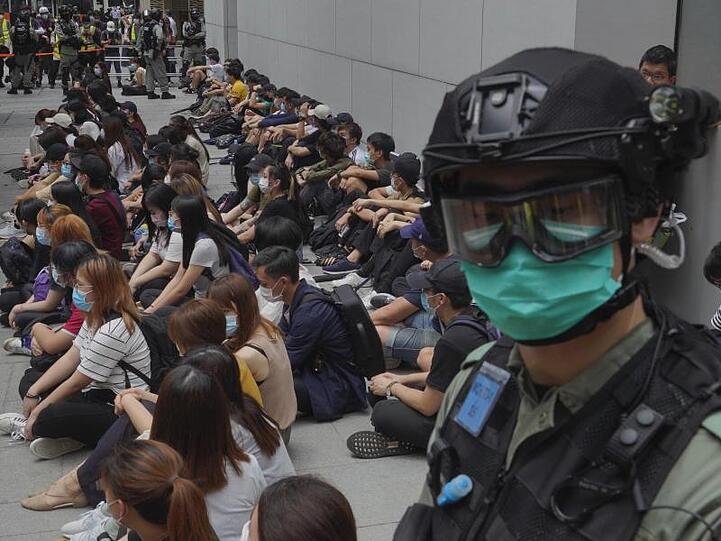 Von Bereitschaftspolizisten festgehaltene regierungskritische Demonstranten sitzen auf dem Boden im Central District von Hongkong.