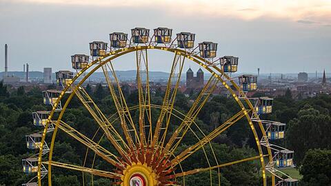 Das Riesenrad des temporären Freizeitparks "NürnBärLand" erhebt sich vor der Stadtkulisse in der Abendsonne.