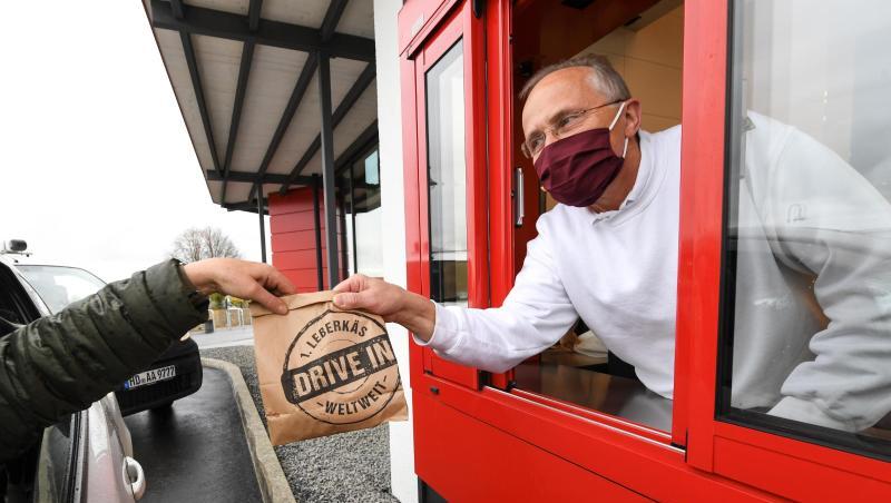 Franz Weinbuch (r) von der Metzergei Weinbuch reicht einem Kunden am Läberkäs-Drive-in-Schalter seine Bestellung ins Auto.