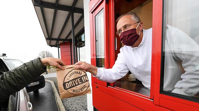 Franz Weinbuch (r) von der Metzergei Weinbuch reicht einem Kunden am Läberkäs-Drive-in-Schalter seine Bestellung ins Auto.