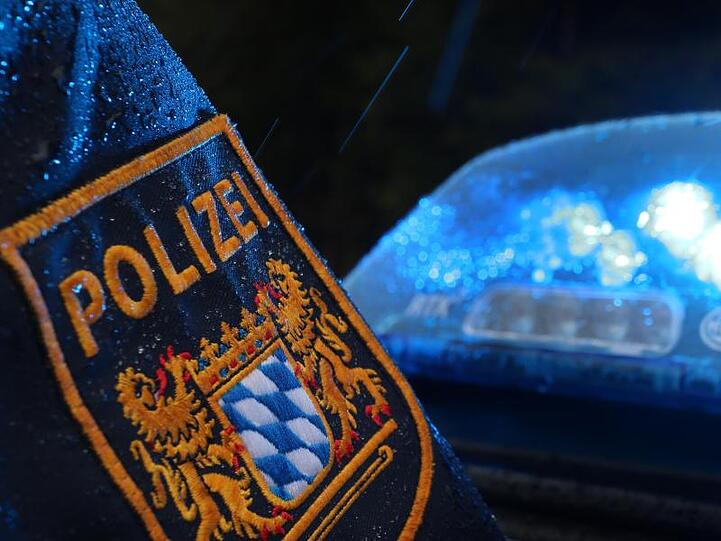 Ein Polizist steht im Regen vor einem Streifenwagen, dessen Blaulicht aktiviert ist. Foto: Karl-Josef Hildenbrand/Archivbild