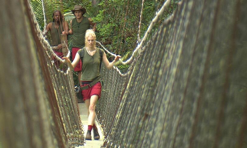 Auf den Weg zu ihrer vierten Dschungelprüfung wird Larissa Marolt bis zur Hängebrücke von Marco Angelini und Mola Adebisi (l.) begleitet.