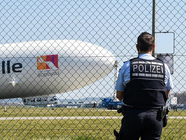 Ein Polizist verfolgt vom Zaun aus den Start des Zeppelin NT (Neue Technik). Foto: Felix Kästle/dpa